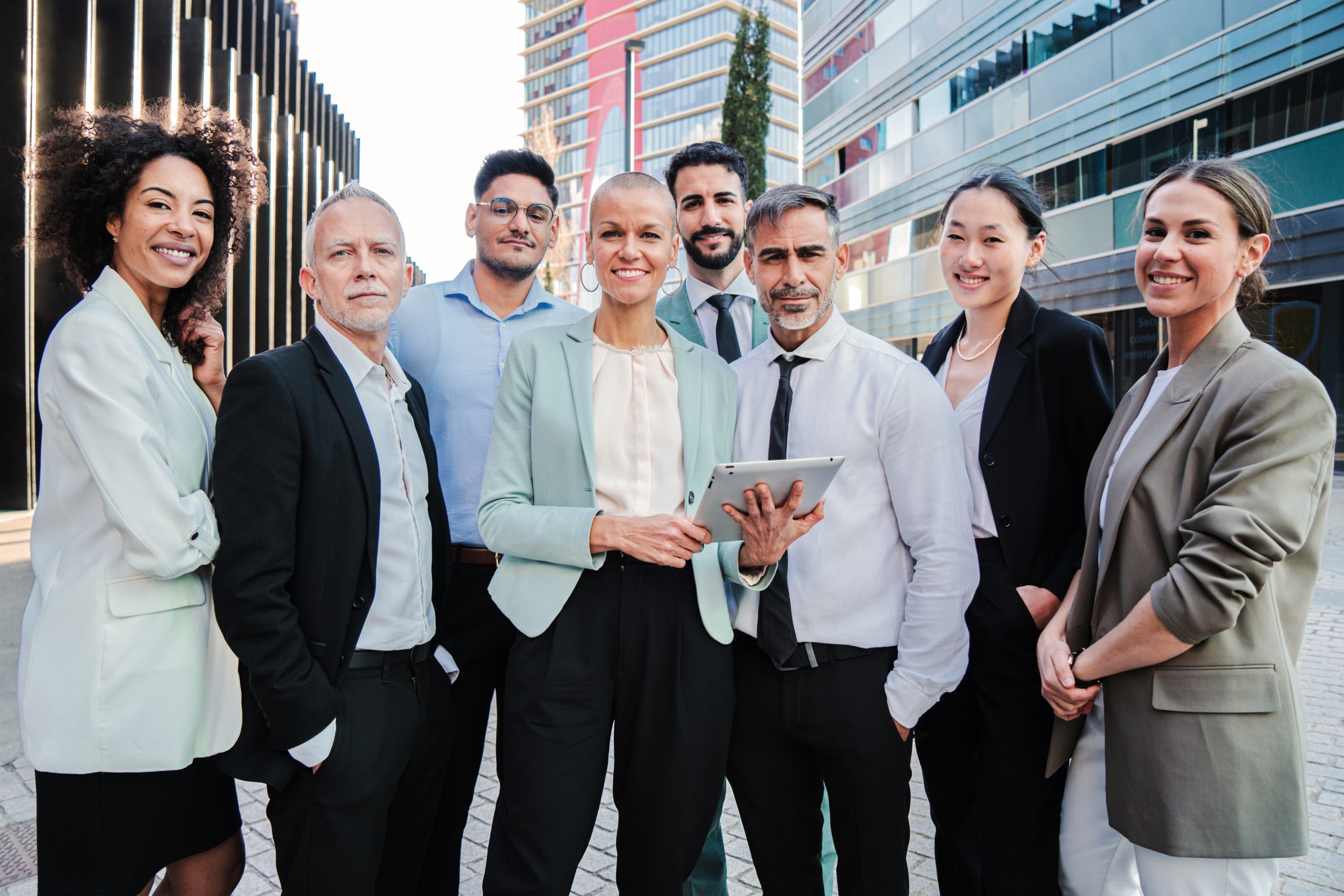 Team work of businesspeople standing at workspace and looking at camera together. Meeting of a crowd of corporate coworkers. Partnership of startup successful employees colaborating at job. Profession. High quality photo